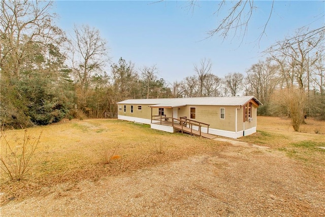 manufactured / mobile home featuring a wooden deck and a front lawn