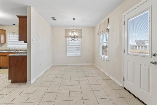 unfurnished dining area featuring an inviting chandelier and light tile patterned flooring