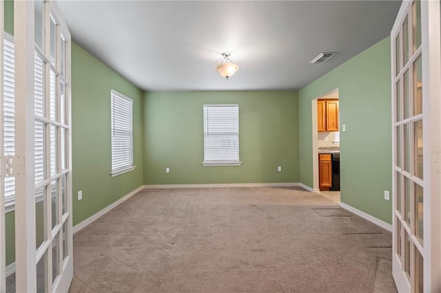 carpeted spare room featuring french doors and a healthy amount of sunlight