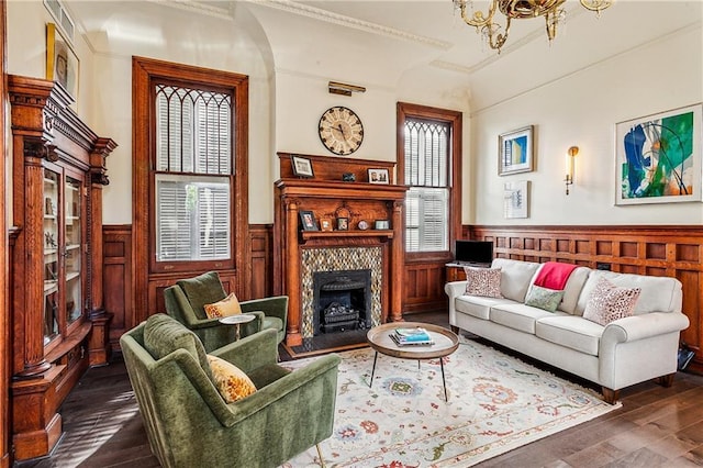 living room featuring a tile fireplace, dark hardwood / wood-style floors, crown molding, and an inviting chandelier