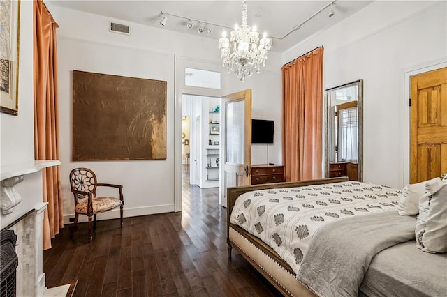 bedroom with an inviting chandelier, track lighting, and dark hardwood / wood-style flooring