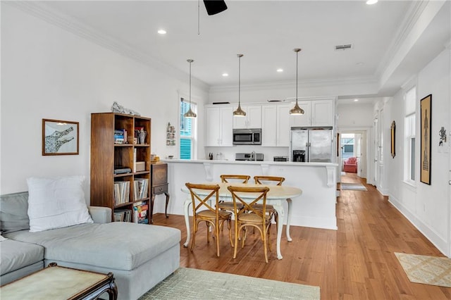 living room featuring ornamental molding, a healthy amount of sunlight, ceiling fan, and light wood-type flooring