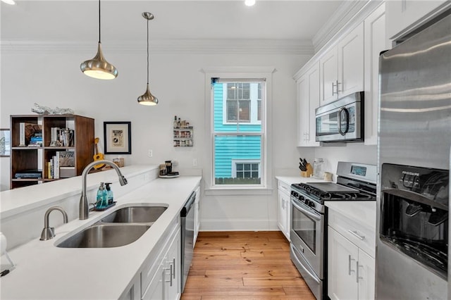 kitchen with appliances with stainless steel finishes, decorative light fixtures, sink, and white cabinets