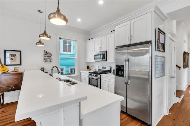 kitchen featuring pendant lighting, white cabinetry, sink, ornamental molding, and stainless steel appliances