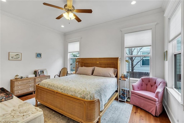 bedroom with hardwood / wood-style flooring, ornamental molding, and ceiling fan