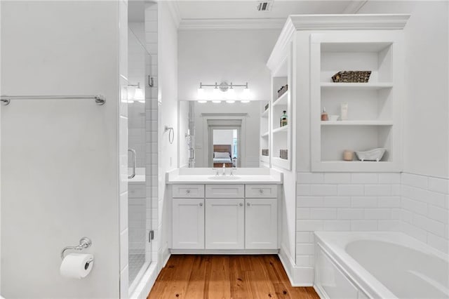 bathroom featuring built in shelves, crown molding, vanity, plus walk in shower, and hardwood / wood-style floors