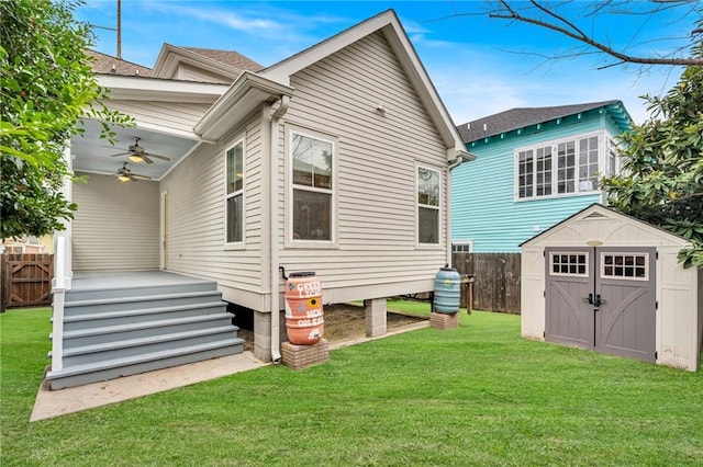 back of house with a shed, a yard, and ceiling fan