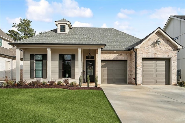 view of front of home featuring a garage, a front yard, and covered porch