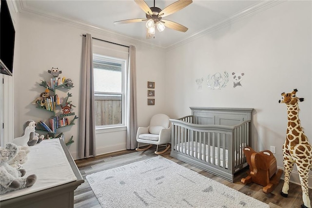 bedroom with crown molding, a nursery area, and dark hardwood / wood-style floors