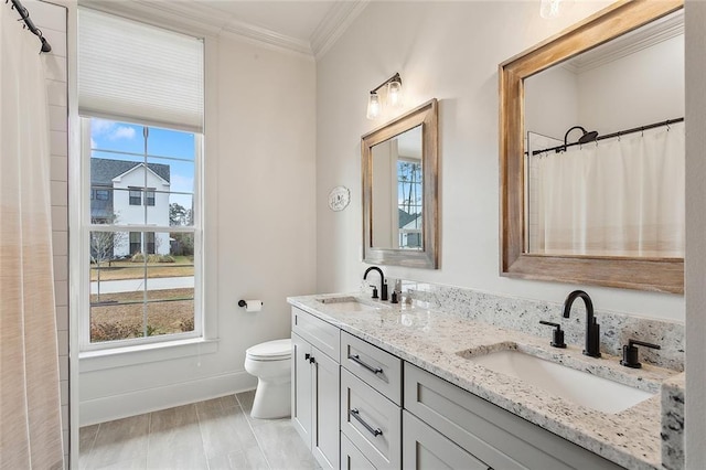 bathroom featuring vanity, ornamental molding, toilet, and a healthy amount of sunlight