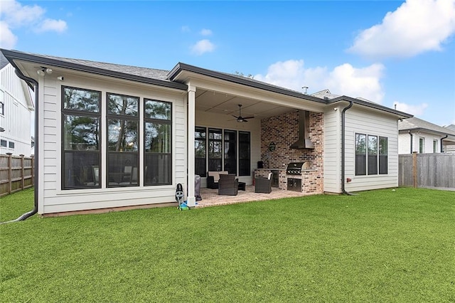 rear view of property with exterior kitchen, a patio, a yard, and ceiling fan