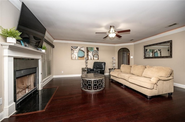 living room with a fireplace, ornamental molding, dark hardwood / wood-style floors, and ceiling fan