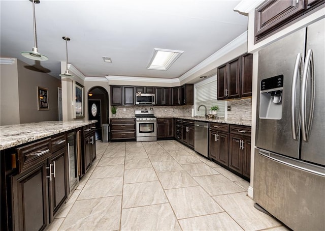 kitchen featuring sink, crown molding, dark brown cabinets, stainless steel appliances, and decorative light fixtures