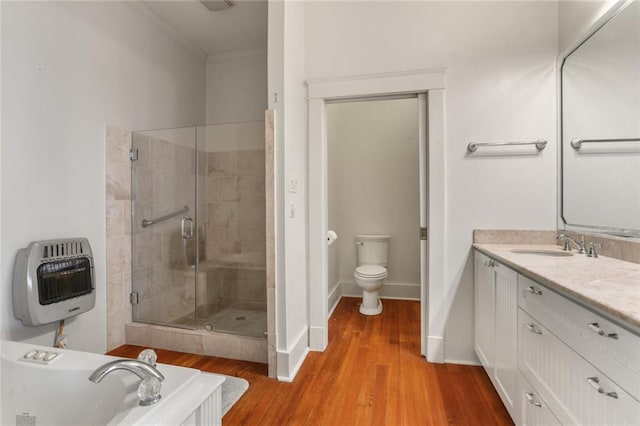 bathroom featuring hardwood / wood-style floors, heating unit, ornamental molding, vanity, and toilet