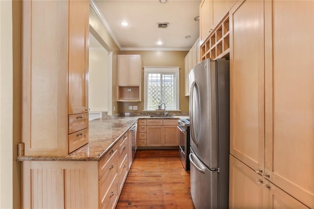 kitchen featuring ornamental molding, light stone counters, light hardwood / wood-style floors, stainless steel appliances, and light brown cabinets