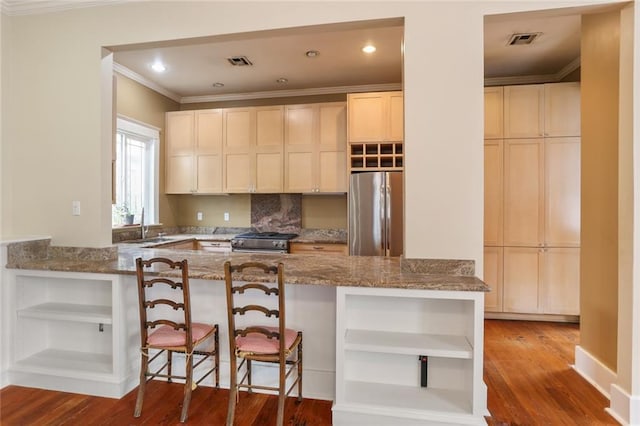 kitchen featuring light hardwood / wood-style flooring, a breakfast bar area, appliances with stainless steel finishes, light stone countertops, and kitchen peninsula