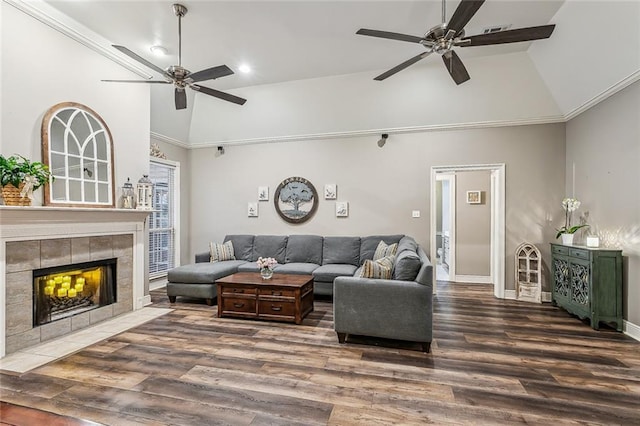 living room with dark hardwood / wood-style flooring, a tiled fireplace, high vaulted ceiling, and ceiling fan