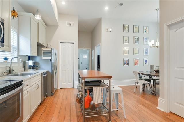 kitchen featuring appliances with stainless steel finishes, pendant lighting, white cabinetry, sink, and light hardwood / wood-style floors