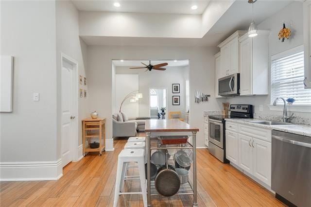 kitchen with sink, hanging light fixtures, a kitchen breakfast bar, stainless steel appliances, and white cabinets