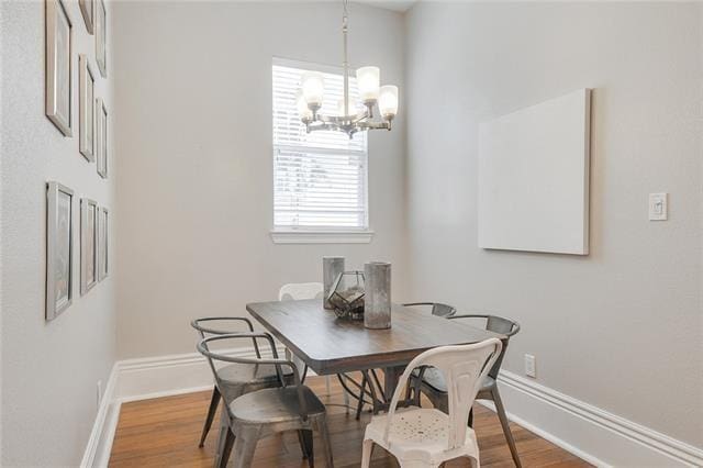 dining area with wood-type flooring and an inviting chandelier