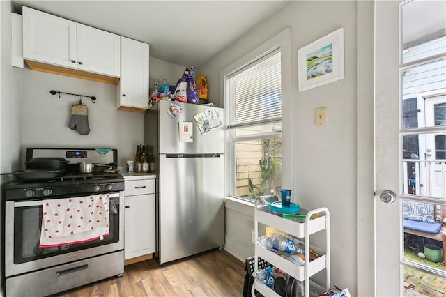 kitchen featuring stainless steel appliances, white cabinets, and light hardwood / wood-style flooring