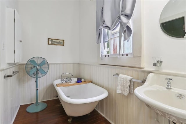 bathroom with hardwood / wood-style flooring, sink, and a tub to relax in