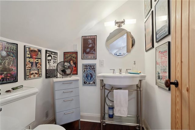 bathroom featuring wood-type flooring, toilet, and vaulted ceiling