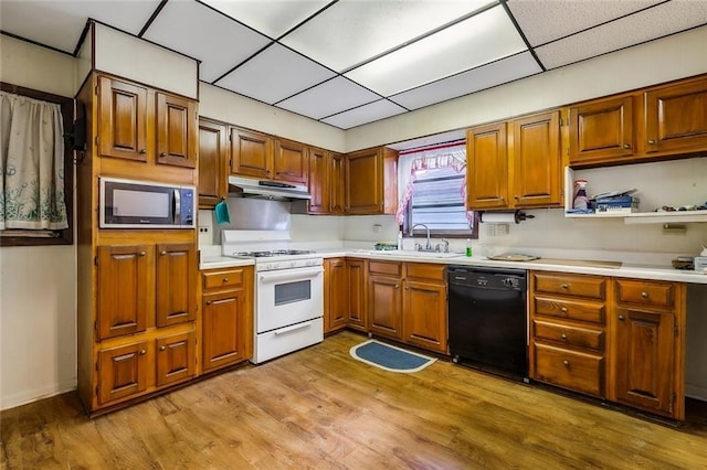 kitchen featuring dishwasher, a sink, built in microwave, under cabinet range hood, and gas range gas stove