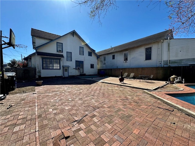 rear view of house with a patio, fence, and an outdoor pool