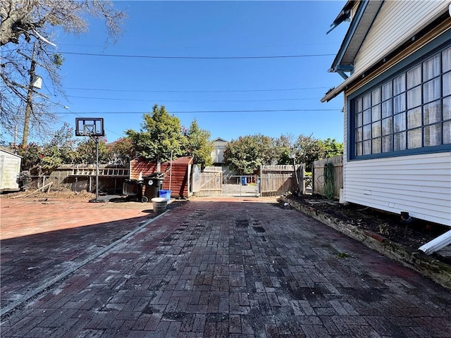 exterior space featuring a gate, fence, and decorative driveway