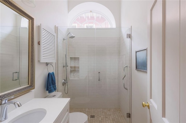 bathroom featuring vanity, toilet, and a shower with shower door