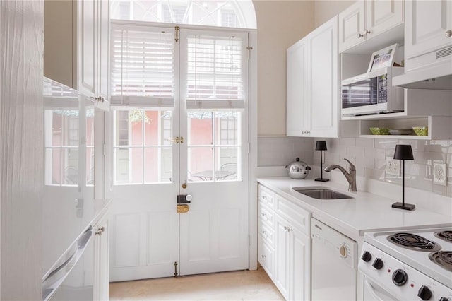 kitchen featuring sink, custom exhaust hood, white cabinetry, white dishwasher, and backsplash