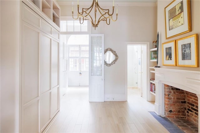 entrance foyer featuring an inviting chandelier, ornamental molding, a high ceiling, and light wood-type flooring