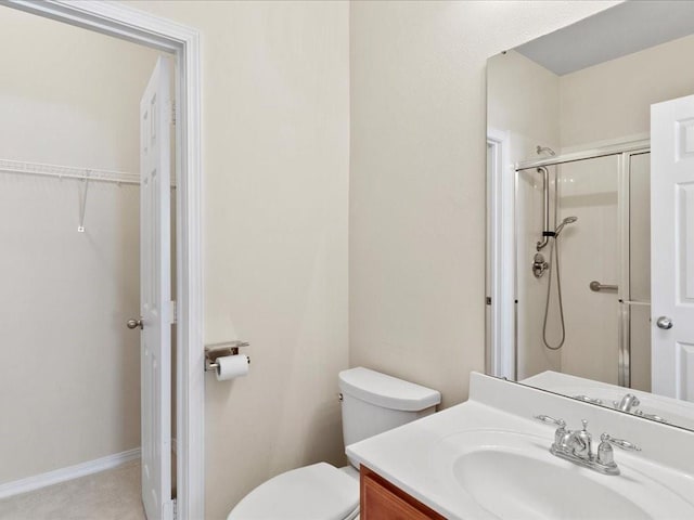 bathroom with toilet, a stall shower, baseboards, and vanity