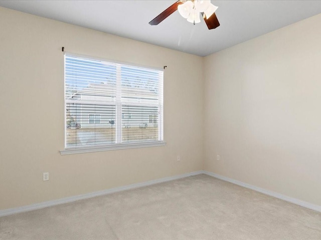 spare room with ceiling fan, baseboards, and light colored carpet