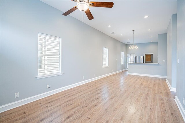 unfurnished living room with ceiling fan with notable chandelier and light wood-type flooring