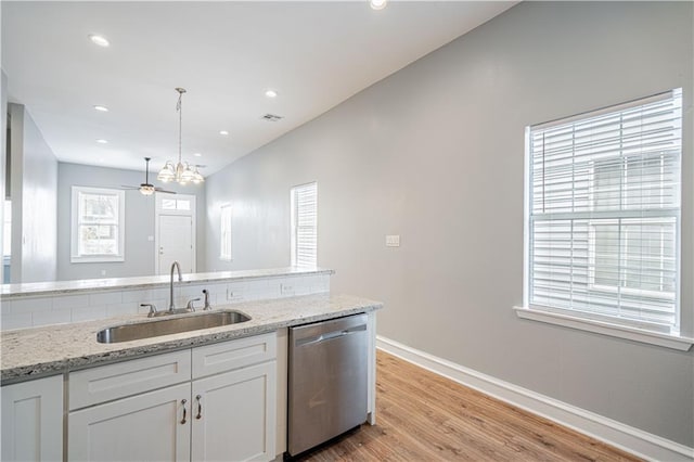 kitchen featuring sink, white cabinets, hanging light fixtures, stainless steel dishwasher, and light stone counters