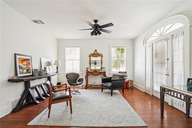 living area featuring plenty of natural light, dark wood-type flooring, and ceiling fan