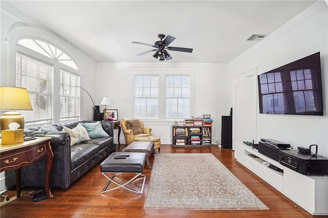 living room with crown molding, dark wood-type flooring, and ceiling fan