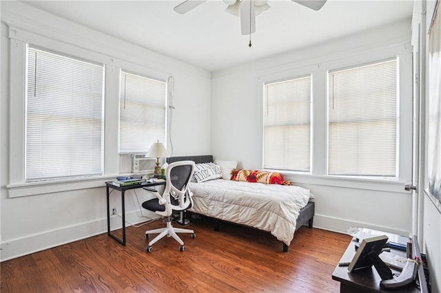 bedroom featuring multiple windows, cooling unit, wood-type flooring, and ceiling fan