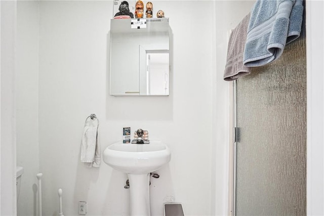 bathroom featuring toilet and a shower with door