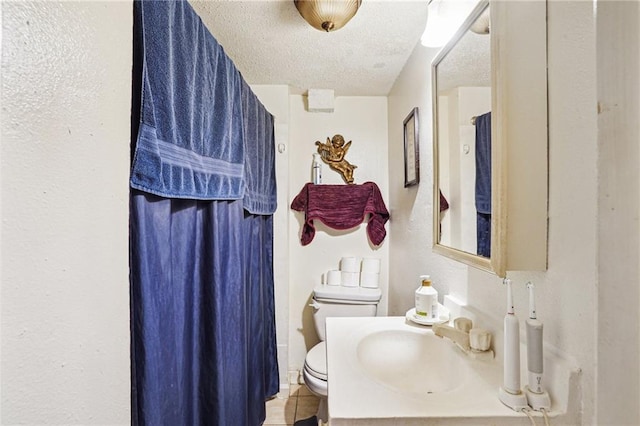 bathroom with vanity, toilet, and a textured ceiling