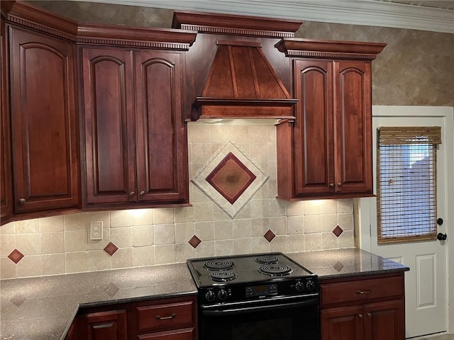 kitchen featuring premium range hood, dark stone countertops, backsplash, ornamental molding, and black electric range