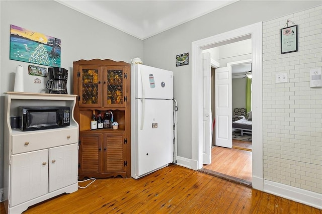 kitchen featuring hardwood / wood-style flooring and white fridge