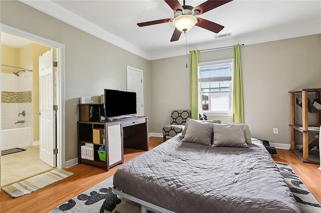 bedroom with ornamental molding, ceiling fan, light hardwood / wood-style floors, and ensuite bath