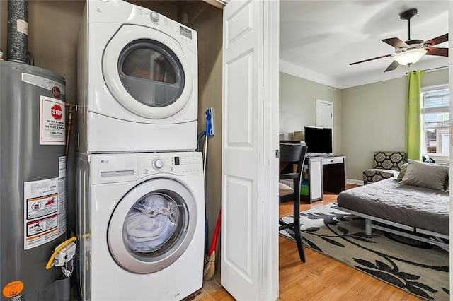 washroom featuring crown molding, light hardwood / wood-style flooring, ceiling fan, stacked washer / dryer, and gas water heater