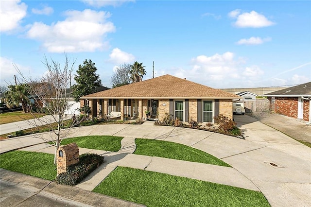 single story home with a front lawn, fence, brick siding, and a shingled roof