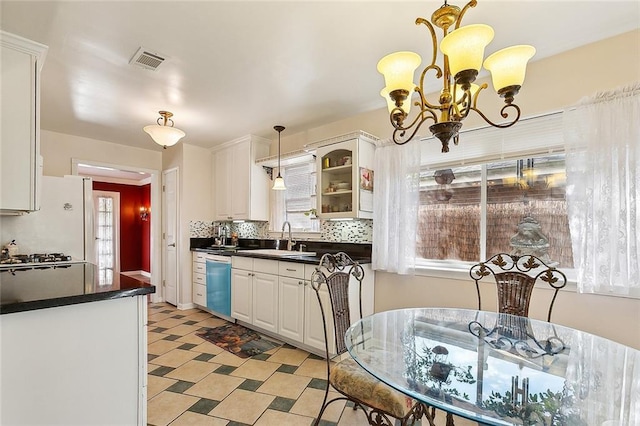 kitchen featuring dishwasher, sink, white cabinets, decorative backsplash, and an inviting chandelier