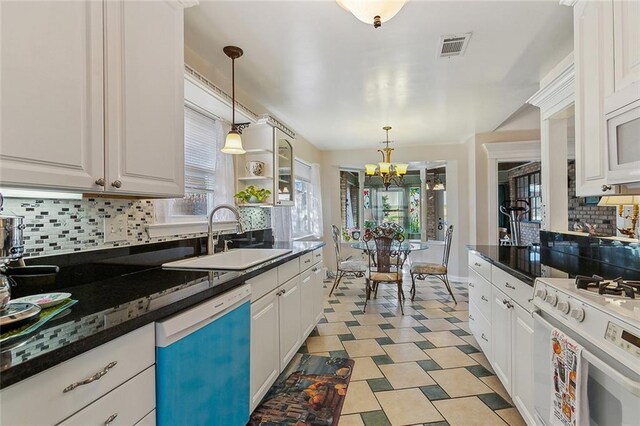 kitchen with decorative light fixtures, tasteful backsplash, sink, white cabinets, and white appliances