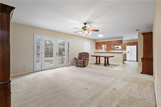 unfurnished living room with french doors, light colored carpet, and ceiling fan